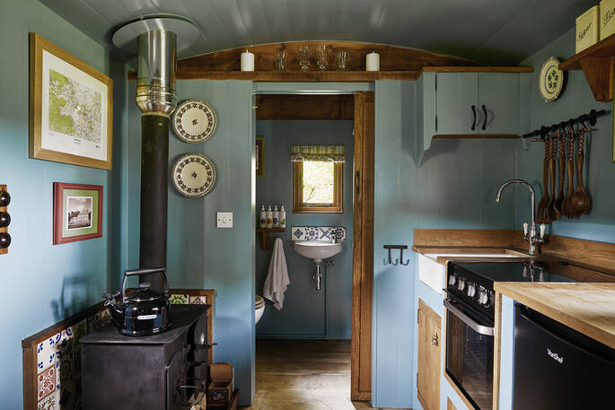 Kitchen leading into the bathroom with a shower, sink and flushing toilet
