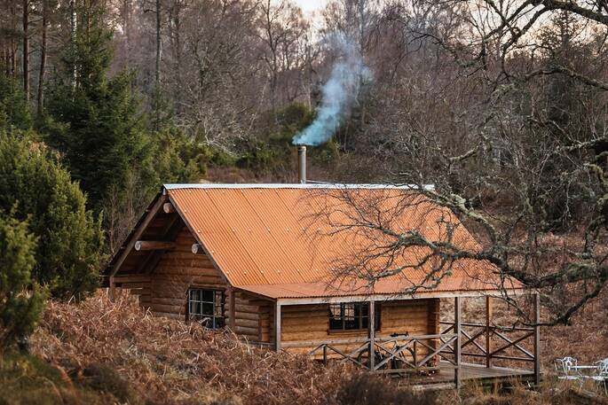 Inshriach Loghouse cabin with chimney smoke, near Aviemore, Highland, Scotland