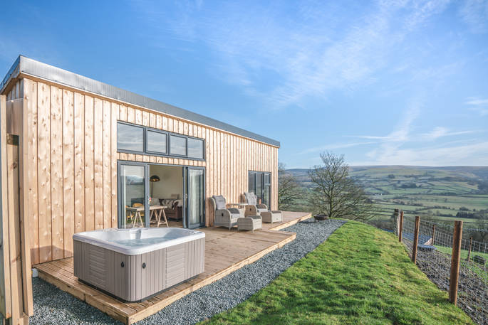 Exterior photo of Shepherds Hill with electric hot tub and seating area on the decking outside at Penlan Farm in Powys 