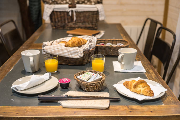 Breakfast laid out on the table with croissants and orange juice at Hautefort Treehouse, Châteaux dans les Arbres, Dordogne, France