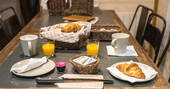 Breakfast laid out on the table with croissants and orange juice at Hautefort Treehouse, Châteaux dans les Arbres, Dordogne, France