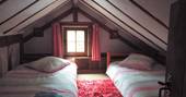 Cosy upstairs bedroom with small window and two comfortable double beds standing alongside a nice cherry rug at Fisherman's Cabin, France