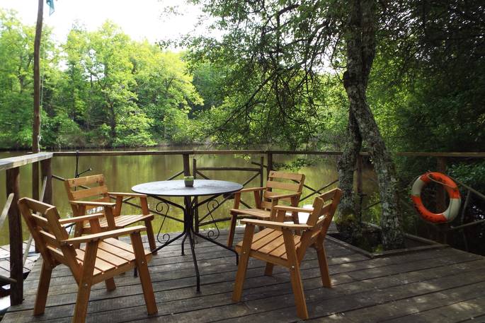 Comfortable al fresco dining area outside on the wooden patio overlooking the water at Covert Cabin, France