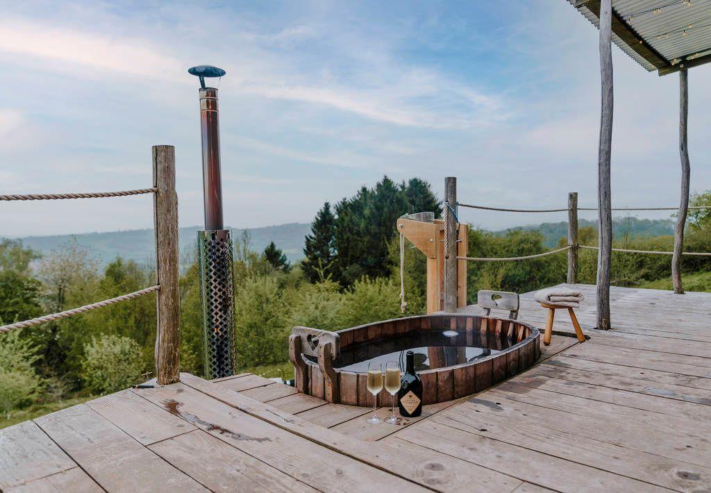 Hot tub in decking with glasses of bubbles and countryside view 
