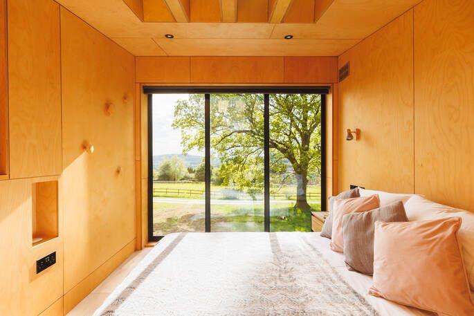 Cabin bedroom with large window and view of countryside 