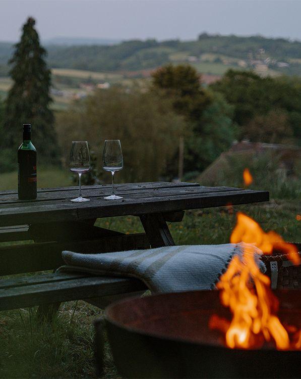 Picnic bench overlooking view with wine, and a fire pit