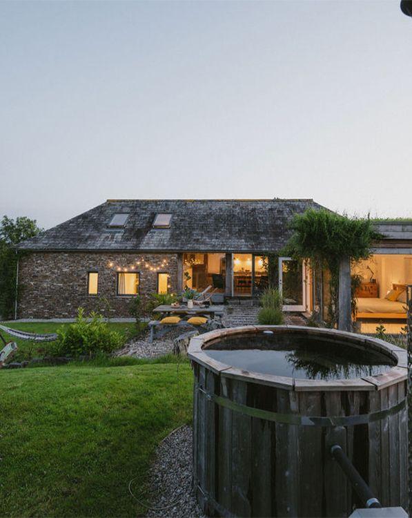 Hinterland House exterior with warm lighting and hot tub 