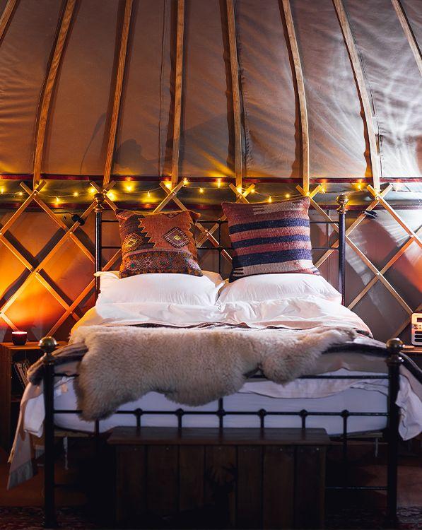 Bed in yurt with fur and fairy lights