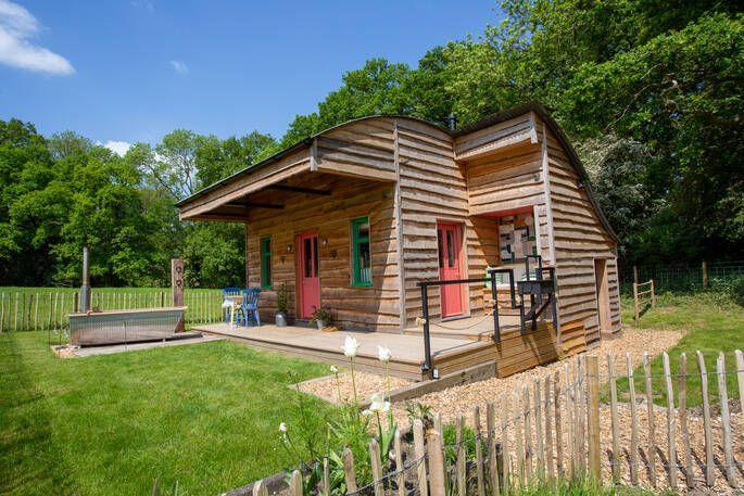 Large wooden cabin with red door and outdoor bath 