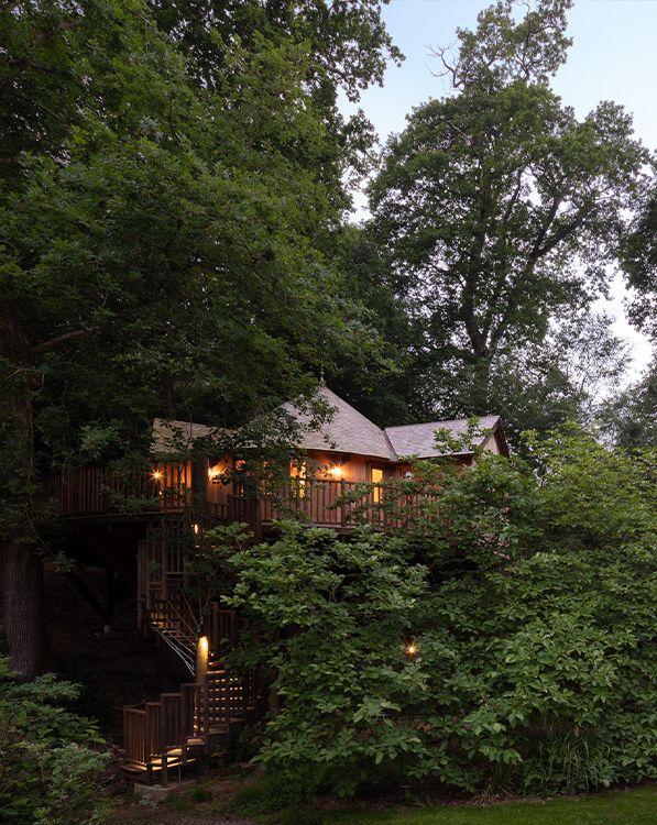 The Buzzardry Treehouse at night with warm lighting 