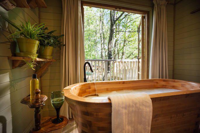 Indoor wooden bath with large window and woodland view 
