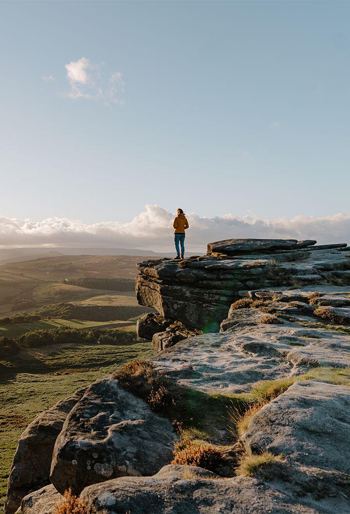 Person standing on the edge of a rocky landscape with countryside view 