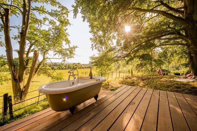 Outdoor bath on decking surrounded in woodland 