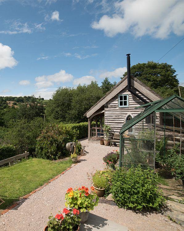 Cabin exterior with greenhouse, flowers and countryside views 