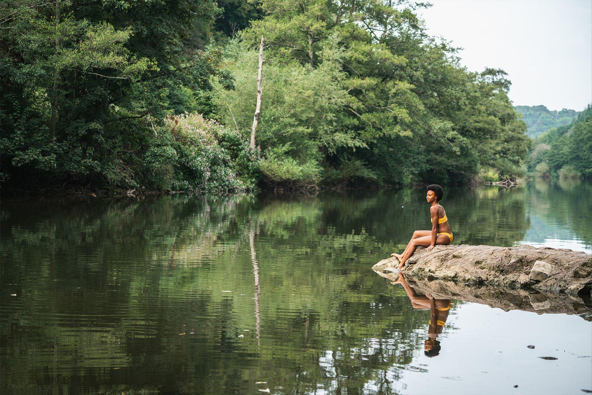 A person sitting on a rock in the river