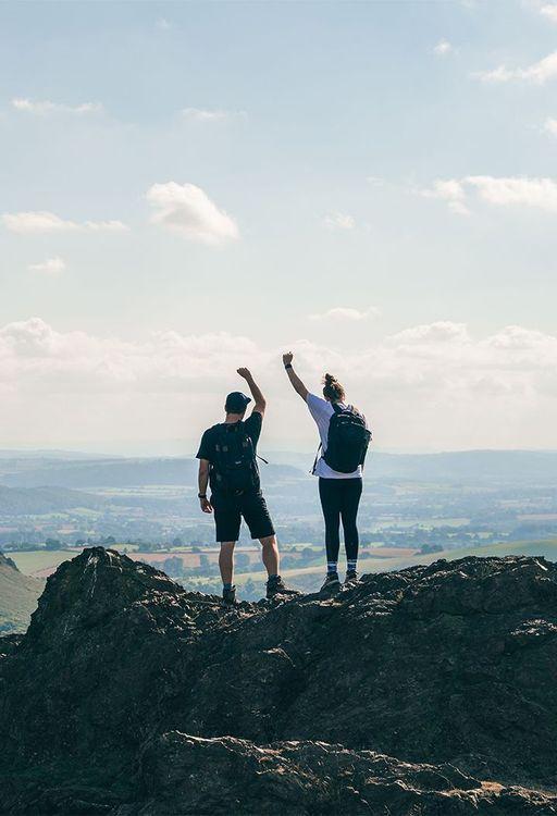 Two people on a mountain cheering 