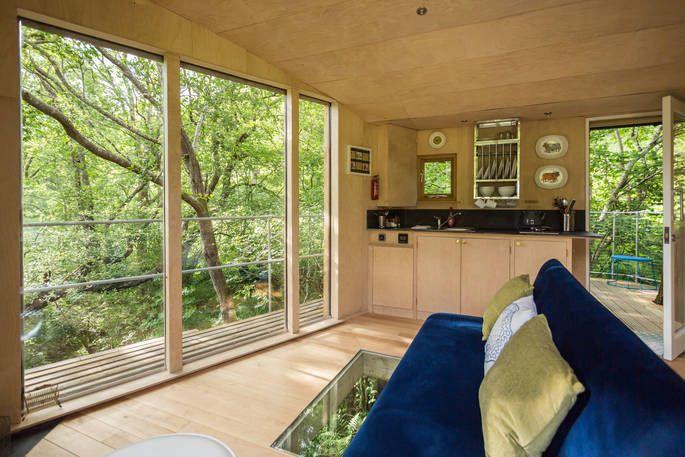 Nyth y Barcud Treehouse interior wit sofa and large window with woodland view 
