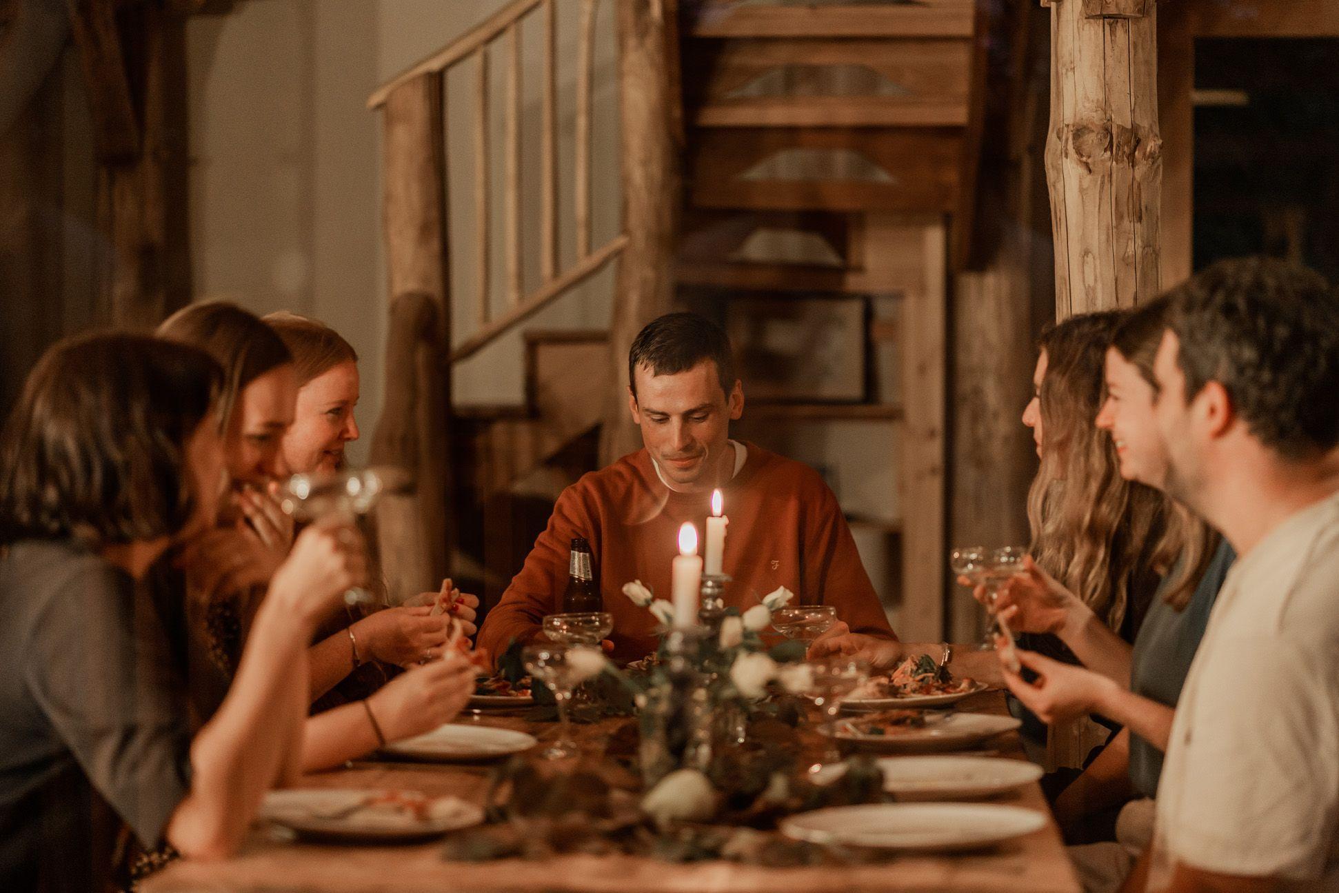 Group eating in a cabin with table and candles 