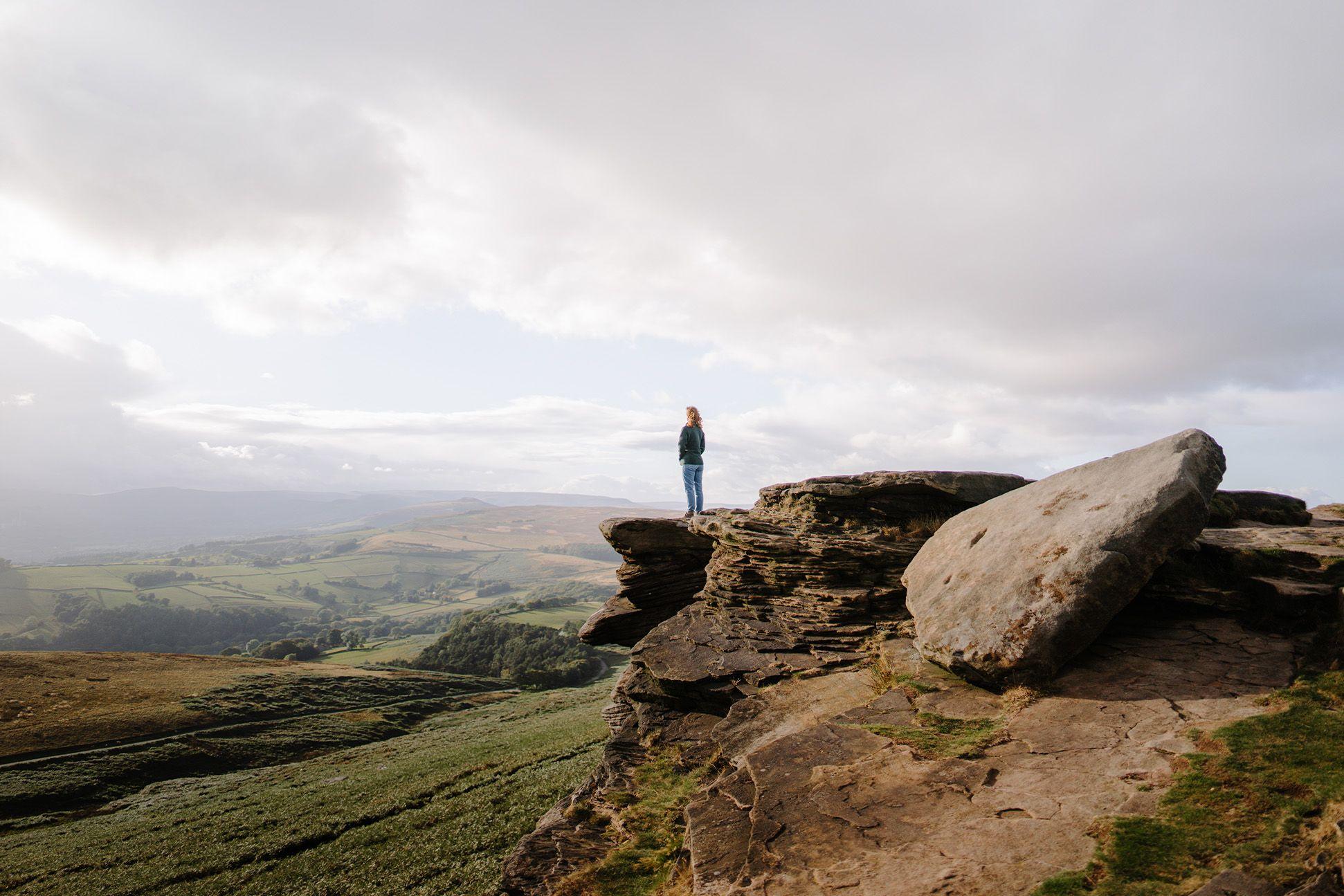Person standing on rock with cloudy sky