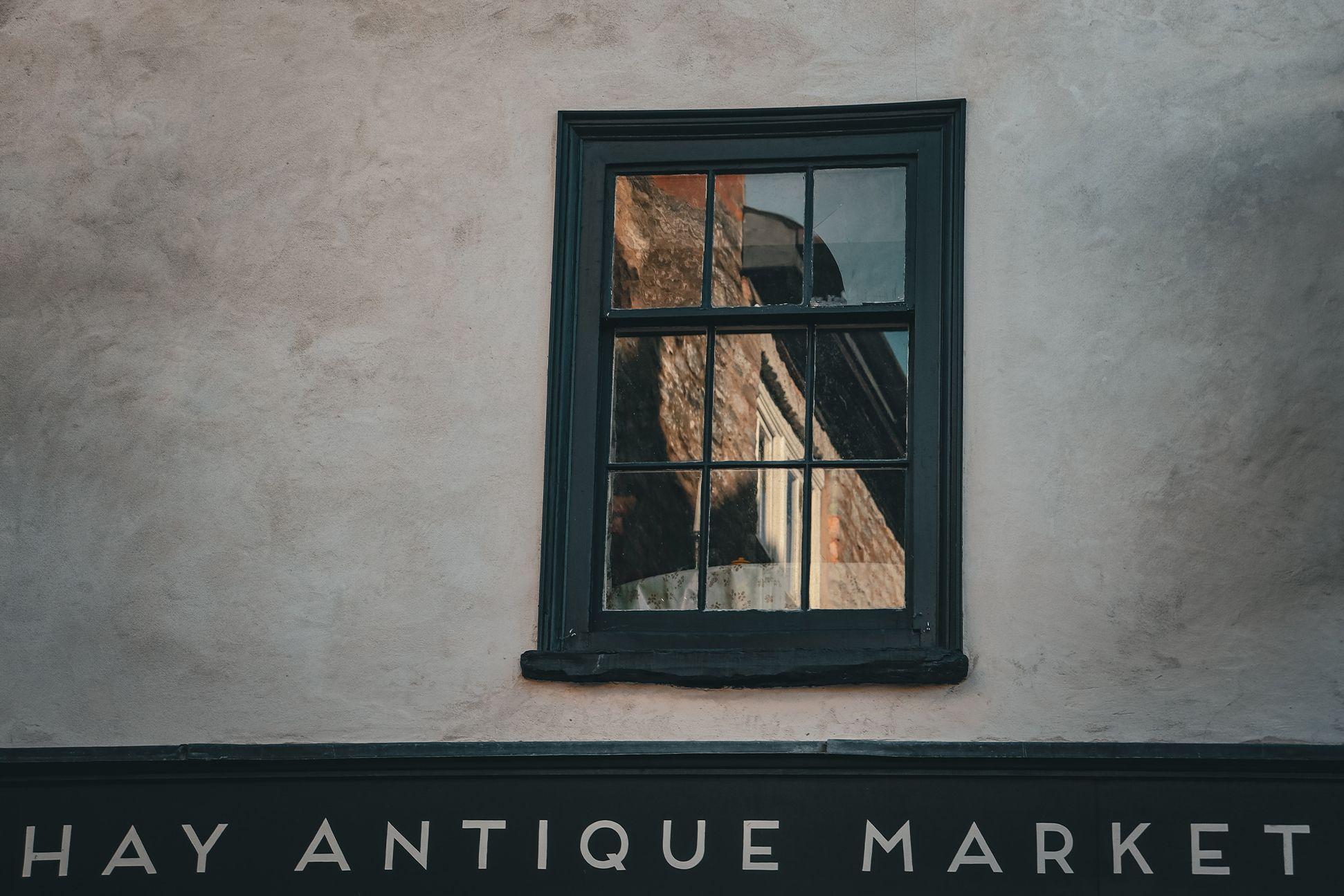 A window above a shop sign that reads "Hay Antique Market" 