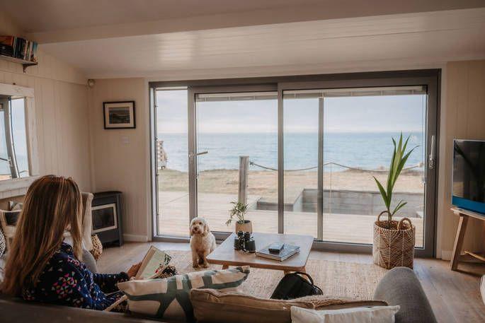 Hive Beach House living room with a large sliding door/ window with view of the beach & sea 