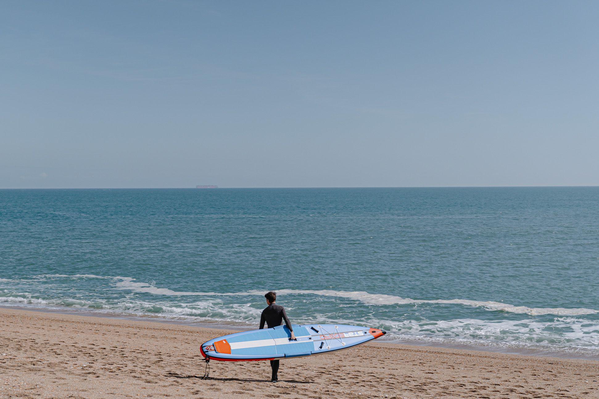 Surfer walking towards the sea 