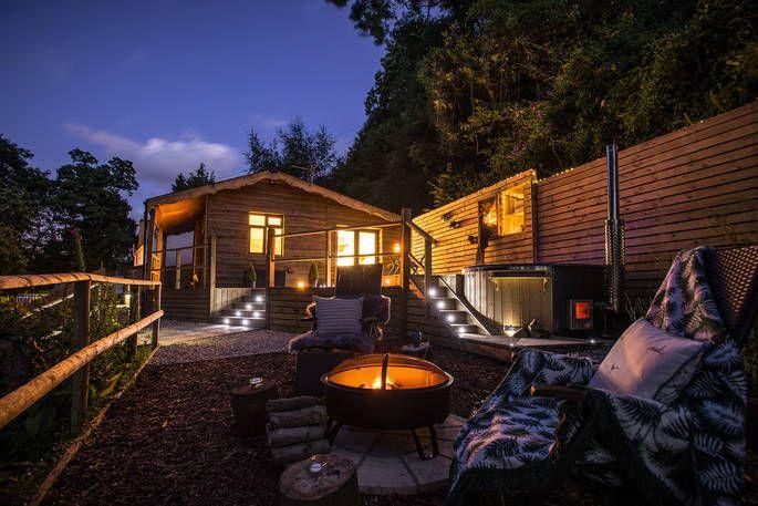 Watsons Cabin at night with warn lighting and cosy firepit 