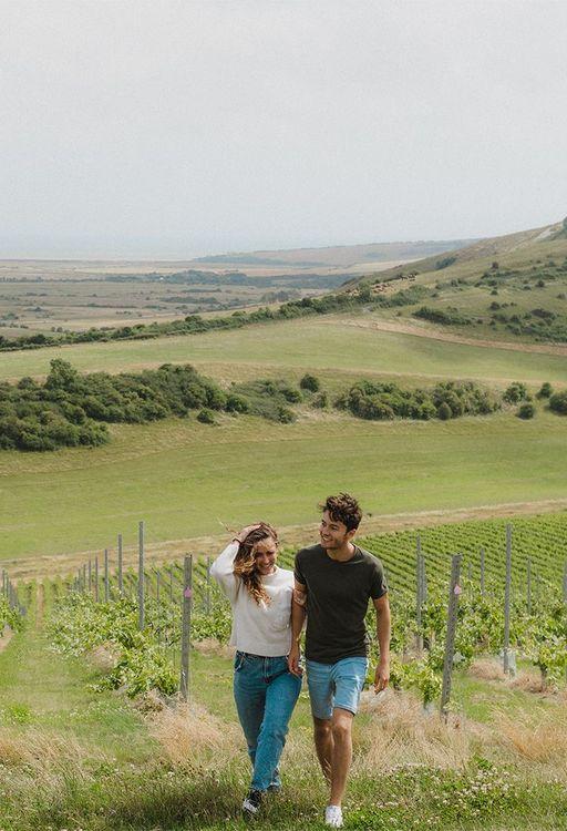 A male and female couple walking through a vineyard 