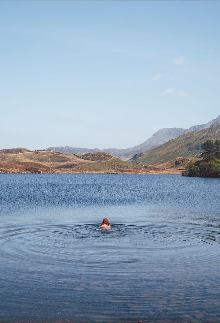 Person wild swimming with views of the mountains 
