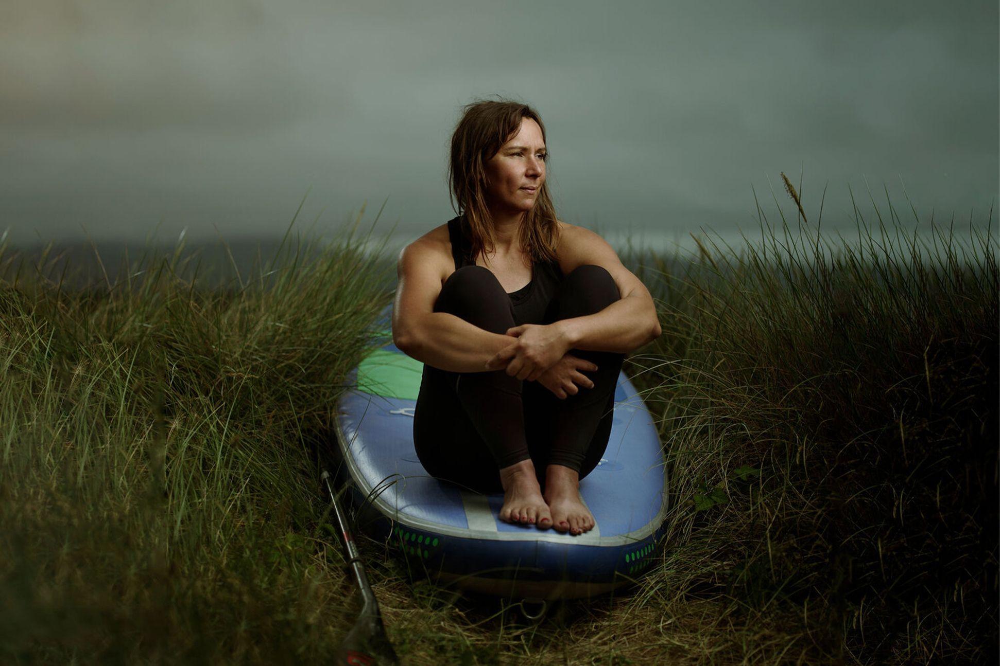 Person sitting on paddle board in grass 