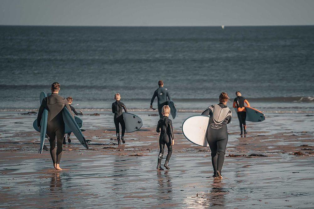 A family heads into the sea to surf