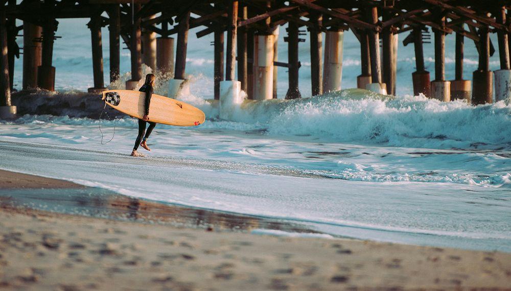 A woman heads out into the water below a pier