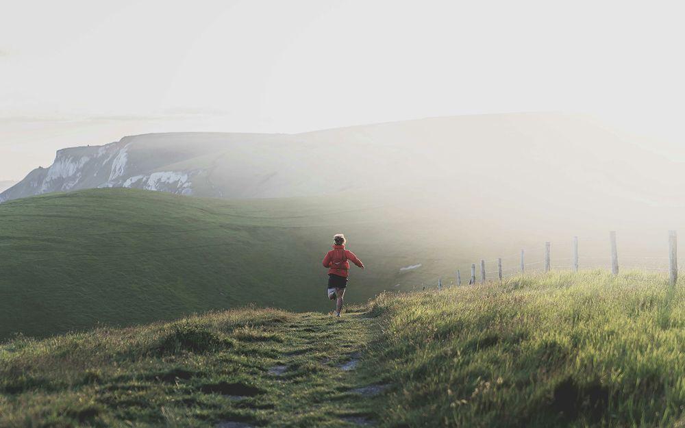 Trail runner heading over hill 