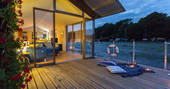 Candles on the outside deck of barge Amelie at night with a warm glow radiating from the interior living space