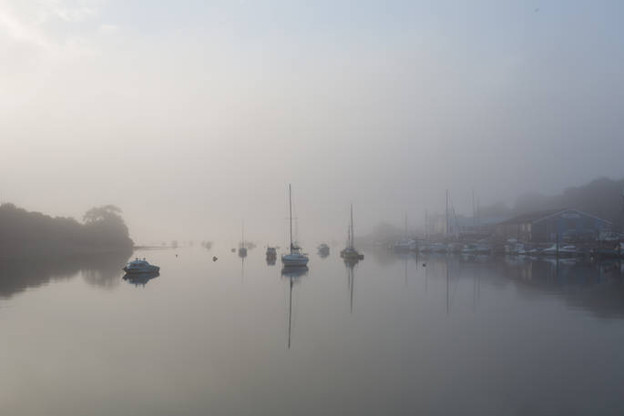 Mist over Penryn River with neighbouring boats bobbing on the water 