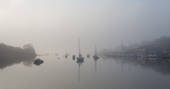 Mist over Penryn River with neighbouring boats bobbing on the water 