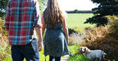 Couple walking through the fields of Cornwall with their dog at Ekopod