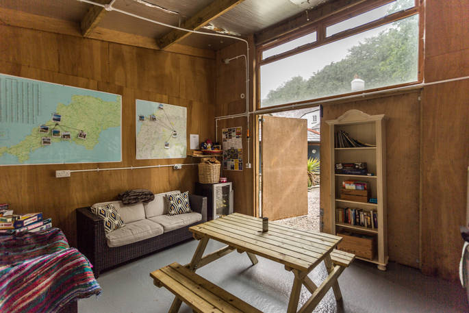 Interior of communal barn at Ekopod with comfortable sofa and picnic table, and books and games to be enjoyed