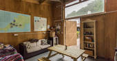 Interior of communal barn at Ekopod with comfortable sofa and picnic table, and books and games to be enjoyed