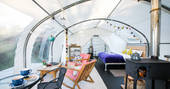 Interior of Steren with cosy modern double bed, seating area and wood-burner at Ekopod
