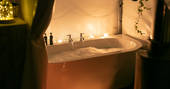 Luxurious bath tub surrounded by candles and filled with bubbles inside of Steren at Ekopod