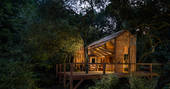 The Danish Cabin lit up in the evening dusk via solar powered lighting at Kudhva in Cornwall
