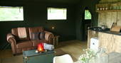 Brown leather sofa and kitchen area in Mabbs, Little Nook Glamping, Cornwall 