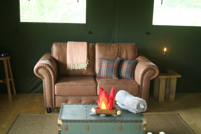 Brown two seater leather sofa with trunk and cushions in front of it in Mabbs, Cornwall