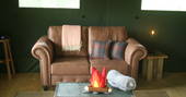 Brown two seater leather sofa with trunk and cushions in front of it in Mabbs, Cornwall