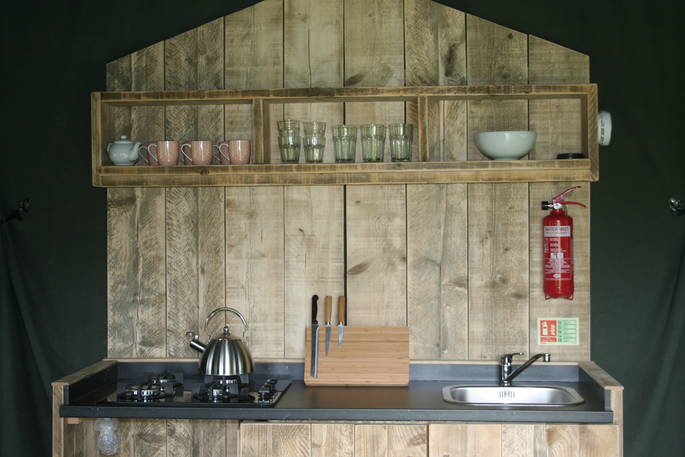 Mabbs kitchen and cooking area with gas stove and shelving unit in the Safari Tent