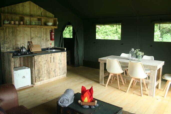 Mabbs wooden dining table with five seats and kitchen area next to it in Little Nook Glamping, Cornwall