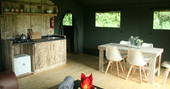 Mabbs wooden dining table with five seats and kitchen area next to it in Little Nook Glamping, Cornwall
