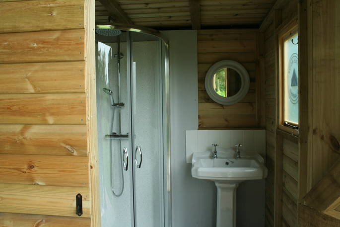Private bathroom with shower and sink inside of hut behind Safari Tent, Cornwall
