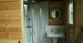Private bathroom with shower and sink inside of hut behind Safari Tent, Cornwall